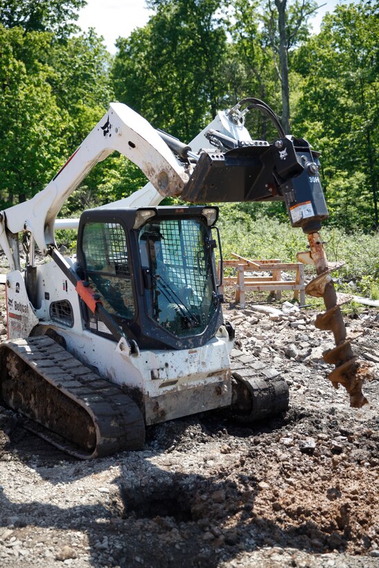 U.S. Marine Lance Cpl. Mitchell R. Neimann (left), heavy equipment operator with Engineer Company C, 6th Engineer Support Battalion, 4th Marine Logistics Group, operates an Bobcat auger to dig a hole at a construction site during exercise Red Dagger at Fort Indiantown Gap, Pa., May 21, 2018.