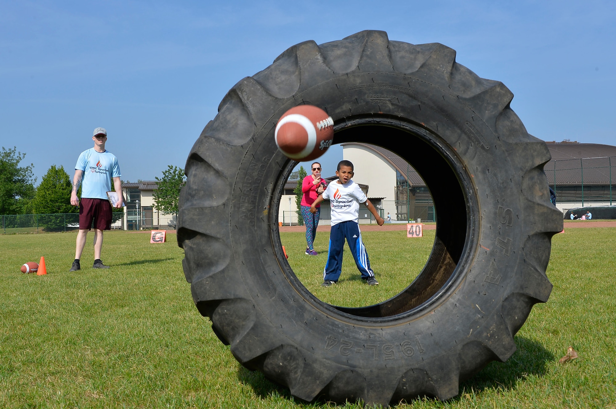 A Kaiserslautern Military Community Summer Special Olympian throws a football through a tire on Ramstein Air Base, Germany, May 18, 2018. The KMC Special Olympics occurs biannually, with one event in the summer and the other in the winter. (U.S. Air Force photo by Senior Airman Joshua Magbanua)