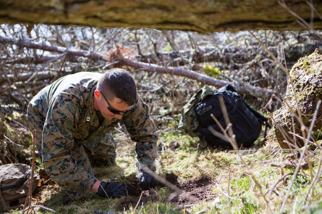 U.S. Marine Corps Capt. Ryan Mathews, a firepower control team leader with 4th Air Naval Gunfire Liaison Company, Force Headquarters Group, pulls up moss for shelter during survival training, in Durness, Scotland, April 26, 2018.