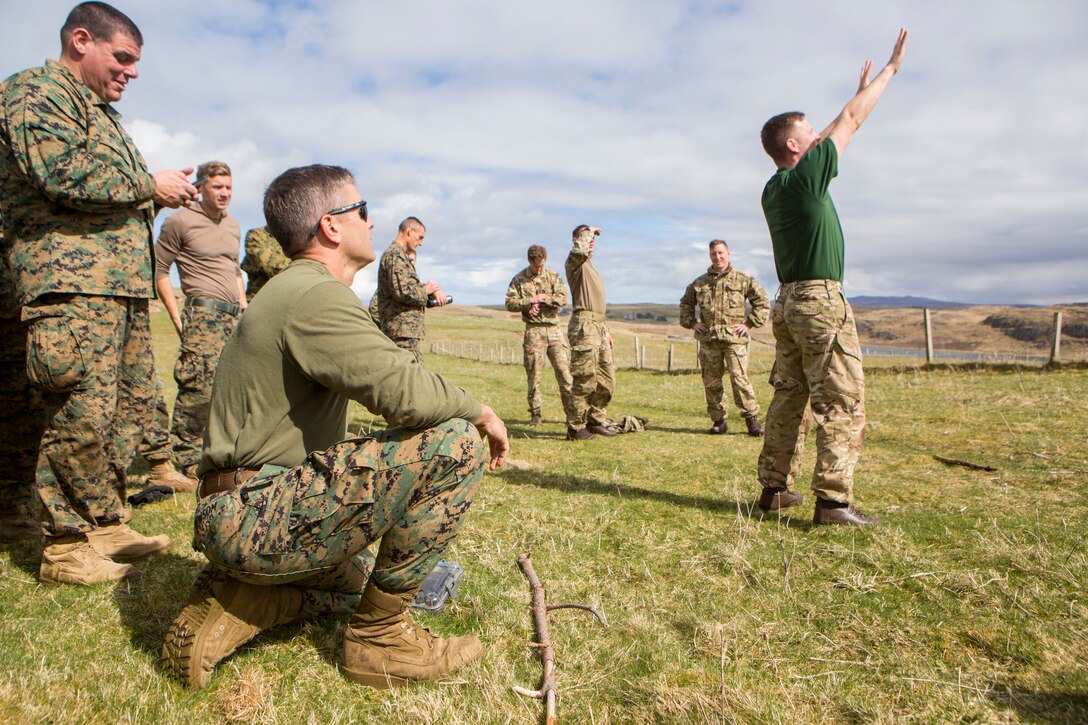 While conducting survival training, British Army Staff Sgt. Steven Kelly (right), survival instructor with 29th Commando Regiment, Artillery Battery, teaches Marines with 4th Air Naval Gunfire Liaison Company, Force Headquarters Group, how to properly tell direction by the placement of hands in the sky, in Durness, Scotland, April 26, 2018.