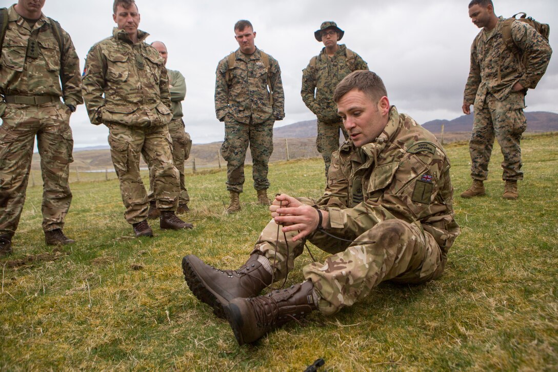 British Army Staff Sgt. Steven Kelly, survival instructor with 29th Commando Regiment, Artillery Battery, shows Marines with 4th Air Naval Gunfire Liaison Company, Force Headquarters Group, how to quickly escape from zip-tie handcuffs with shoelaces from his boots, during survival training, in Durness, Scotland, April 26, 2018.
