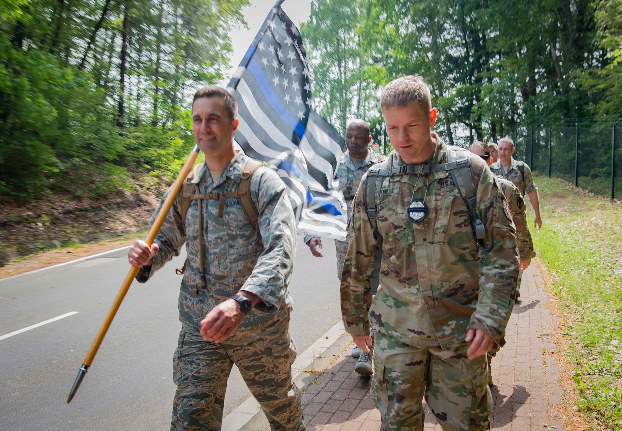Kaiserslautern Military Community service members take part in a 24-hour ruck march while bearing the Thin Blue Line Flag on Vogelweh Air Station, Germany, May 17, 2018. The Thin Blue Line Flag honors police officers; the black background represents the fallen, and the blue line represents the protective barrier that police officers uphold against danger.