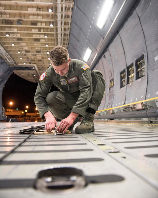 U.S. Air Force Senior Airman Robert Harold, loadmaster with the 22nd Airlift Squadron, Travis Air Force Base, Calif., secures a pulley on a C-5M Super Galaxy.