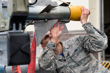 Airman 1st Class Emmanuel Pena, a 525th Aircraft Maintenance Unit weapons loader, checks over a munition for loading during the Wing Weapons Load Crew 1st Quarter Competition May 18, 2018, at Joint Base Elmendorf-Richardson, Alaska. The quarterly competition consists of two AMU weapons-section teams going head-to-head for time and accuracy. A weapons load crew is a group of three people responsible for preparing and loading munitions onto an aircraft.