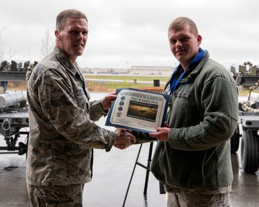 U.S. Air Force Col. Mathew Powell, commander of the 3rd Maintenance Group, presents Staff Sgt. Brandon Ford with the Weapons Supervisor of the Quarter award after the Wing Weapons Load Crew 1st Quarter Competition May 18, 2018, at Joint Base Elmendorf-Richardson, Alaska. The quarterly competition consists of two AMU weapons-section teams going head-to-head for time and accuracy.