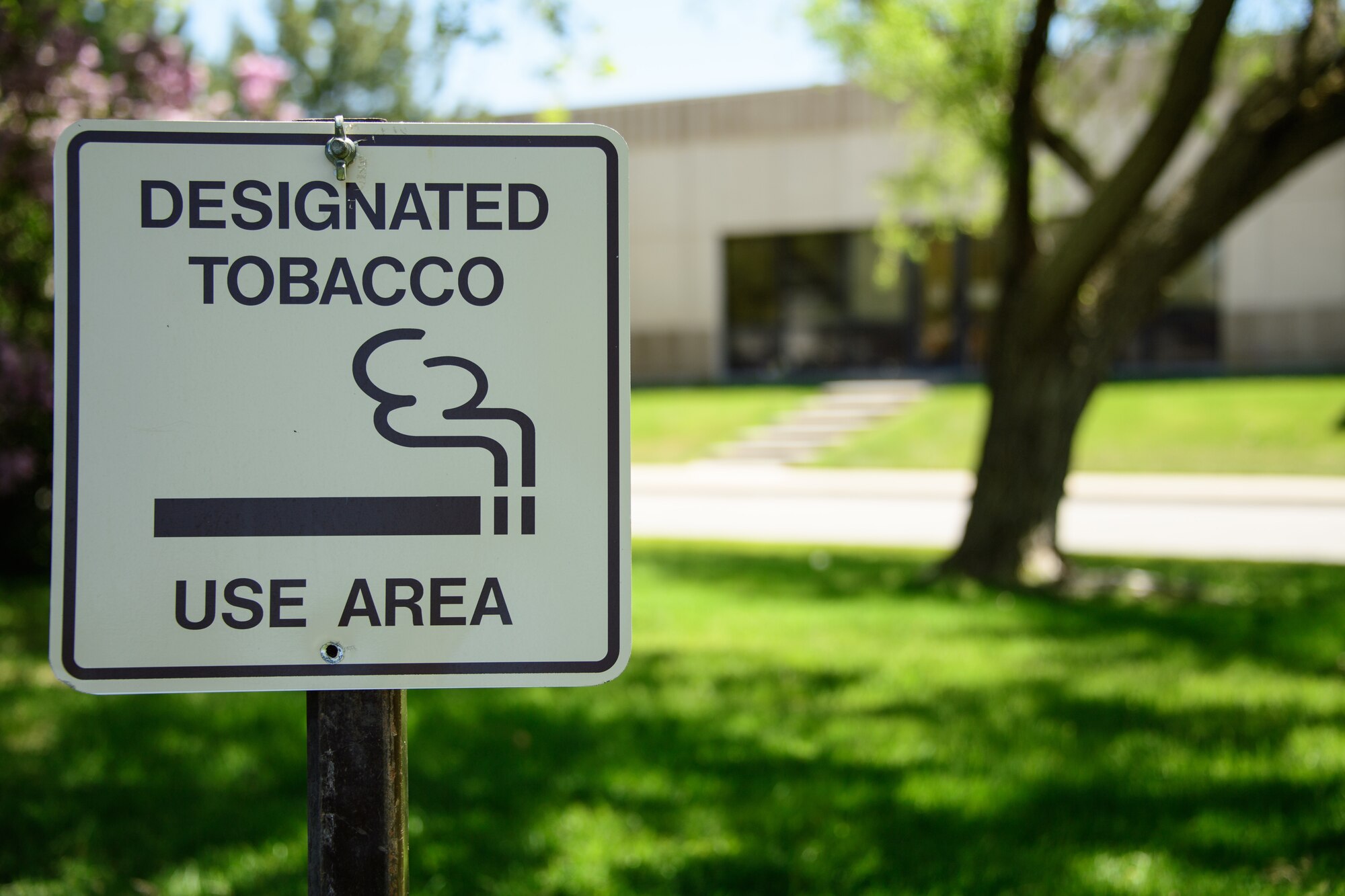 A sign marks the newly designated tobacco use area for the Hill medical campus, May 8, 2018, Hill Air Force Base, Utah. All tobacco use areas were removed from the campus April 27, 2018. The only tobacco use area for visitors and occupants of the campus in located north and across the street from the base clinic, building 570. (U.S. Air Force photo by R. Nial Bradshaw)