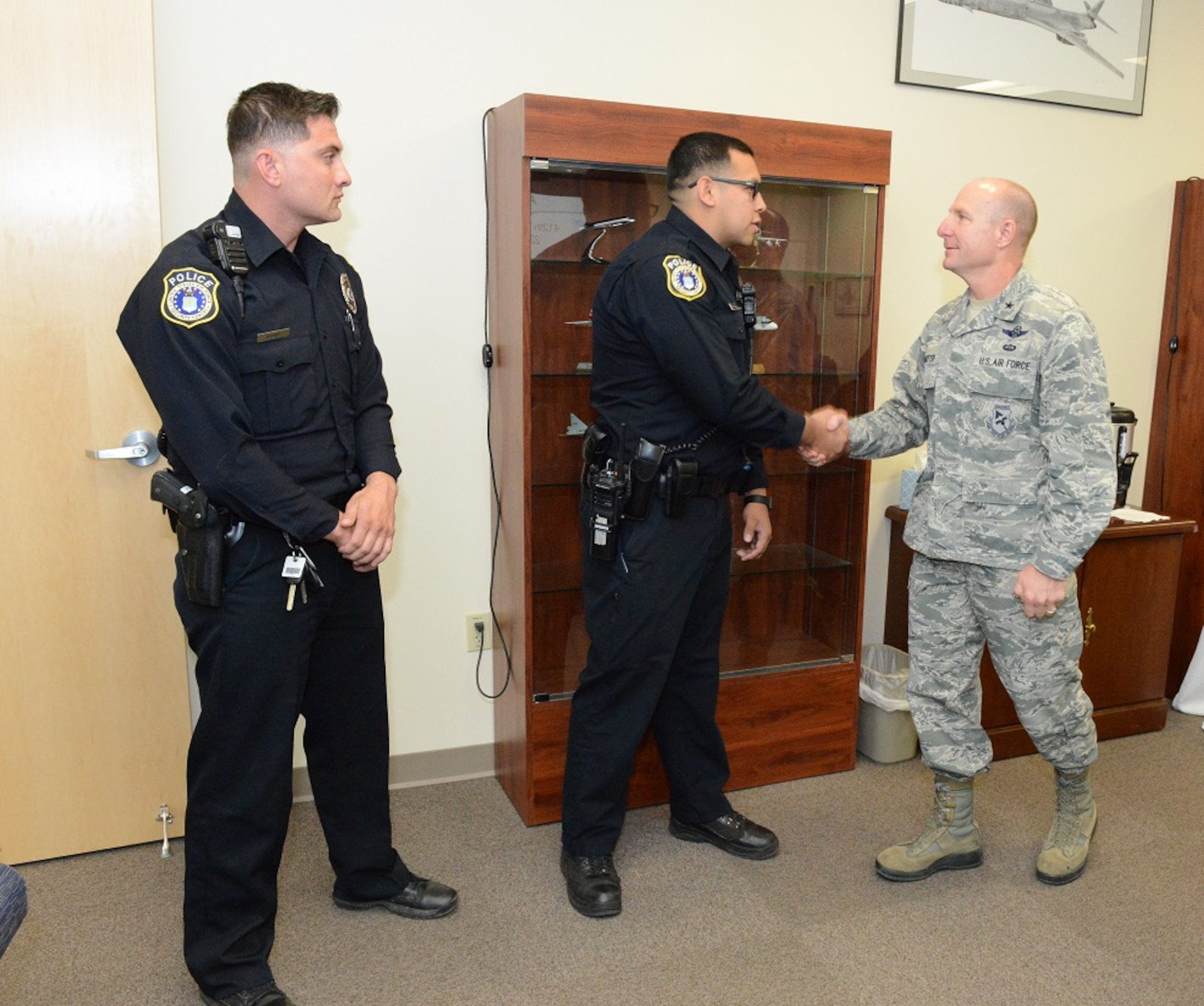 From right to left: Brig. Gen. Carl Schaefer, 412th Test Wing commander, presents Officers Randy Plata and Miguel Madrid test wing coins May 22 to thank them for actions they took during a “gate runner” incident in April. (U.S. Air Force photo by Kenji Thuloweit)