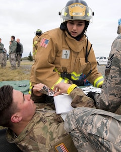 Airman 1st Class Brittney Jordan, a 673d Civil Engineer Squadron (CES) firefighter, covers a simulated victim with an emergency blanket during an active-shooter exercise at Joint Base Elmendorf-Richardson, Alaska, May 17, 2018. The 673d CES fire and emergency services participated in an exercise in preparations for the Arctic Thunder Open House scheduled to take place June 30 and July 1. The exercise is used to test their capabilities in challenging circumstances and provide training for possible incidents.