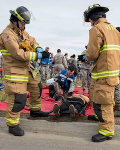Firefighters from the 673d Civil Engineer Squadron (CES) fire and emergency services, put additional gloves on before picking up a simulated victim for transport during an active-shooter exercise at Joint Base Elmendorf-Richardson, Alaska, May 17, 2018. The 673d CES participated in an exercise in preparations for the Arctic Thunder Open House scheduled to take place June 30 and July 1. The exercise is used to test their capabilities in challenging circumstances and provide support to medical personnel throughout the scenario.