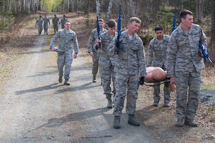 A team with the 673d Security Forces Squadron recuperates while carrying a 200 pound dummy to the forward operating base training station at the Defenders Day Challenge during Police Week on Joint Base Elmendorf-Richardson, Alaska, May 16, 2018. Carrying the litter to the FOB is a part of Tactical Combat Casualty Care. TCCC involves three stages; care under fire, tactical field care, and tactical evacuation care.