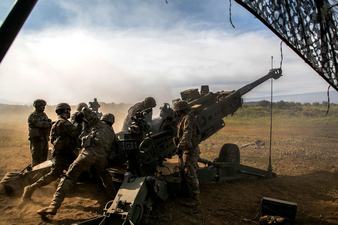 Soldiers load a 155 mm artillery round into an M777 howitzer.
