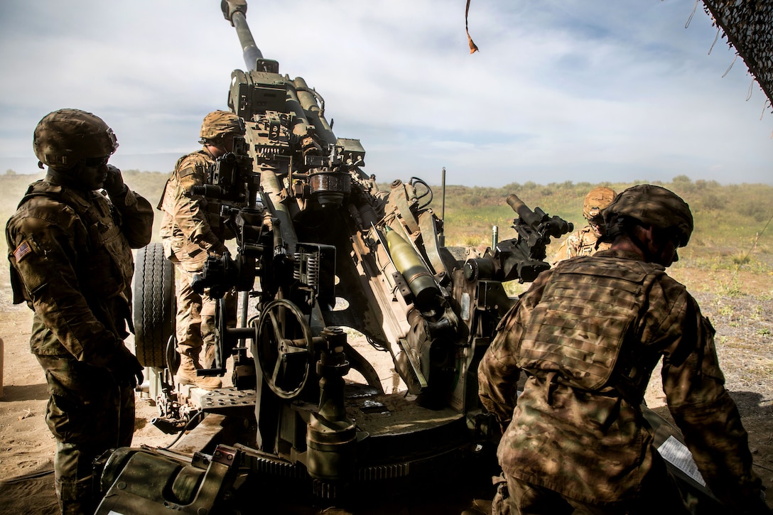 Soldiers prepare to load a 155 mm artillery round into an M777 howitzer.