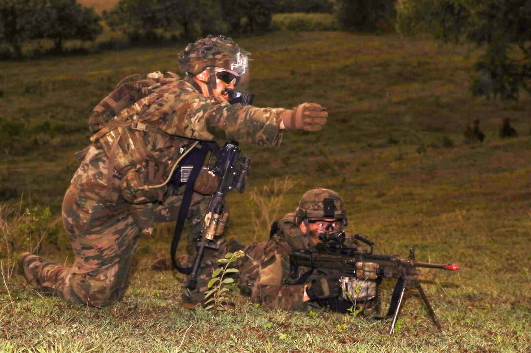 A soldier gives firing directions to a squad member.