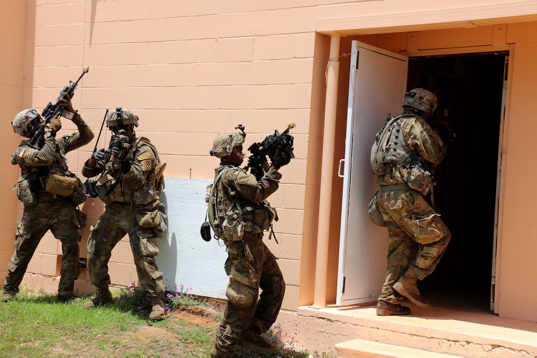 Soldiers provide security while team members enter and search a building.