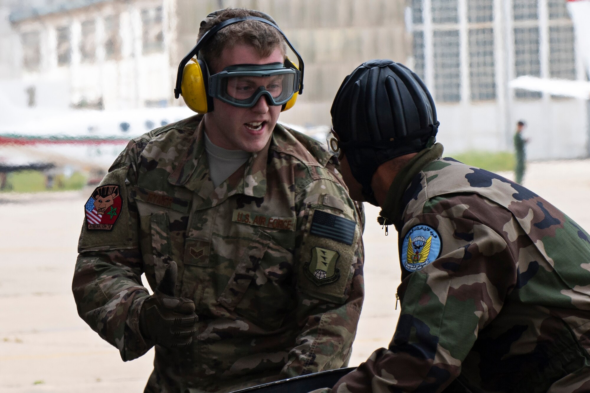 U.S Air Force Senior Airmen Dylan Rymer, 435th Contingency Response Group mobile aerial port journeyman and a Royal Morocann Armed Forces service member move barrels under a cargo load during a combat offload training for Exercise African Lion 18, April 23, 2018 at Kenitra Air Base, Morocco.