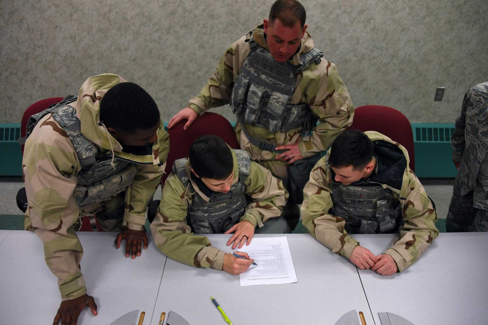 Members of the 319th Security Forces Squadron work together during a readiness competition to complete a written test on chemical, biological, radiological and nuclear weapons May 18, 2018, on Grand Forks Air Force Base, North Dakota. Units across the base created teams of Airmen to participate in the competition, testing their knowledge and application of topics to include CBRN, self-aid and buddy care, weapons assembly, hand-to-hand combat and map-reading. (U.S. Air Force photo by Airman 1st Class Elora J. Martinez)