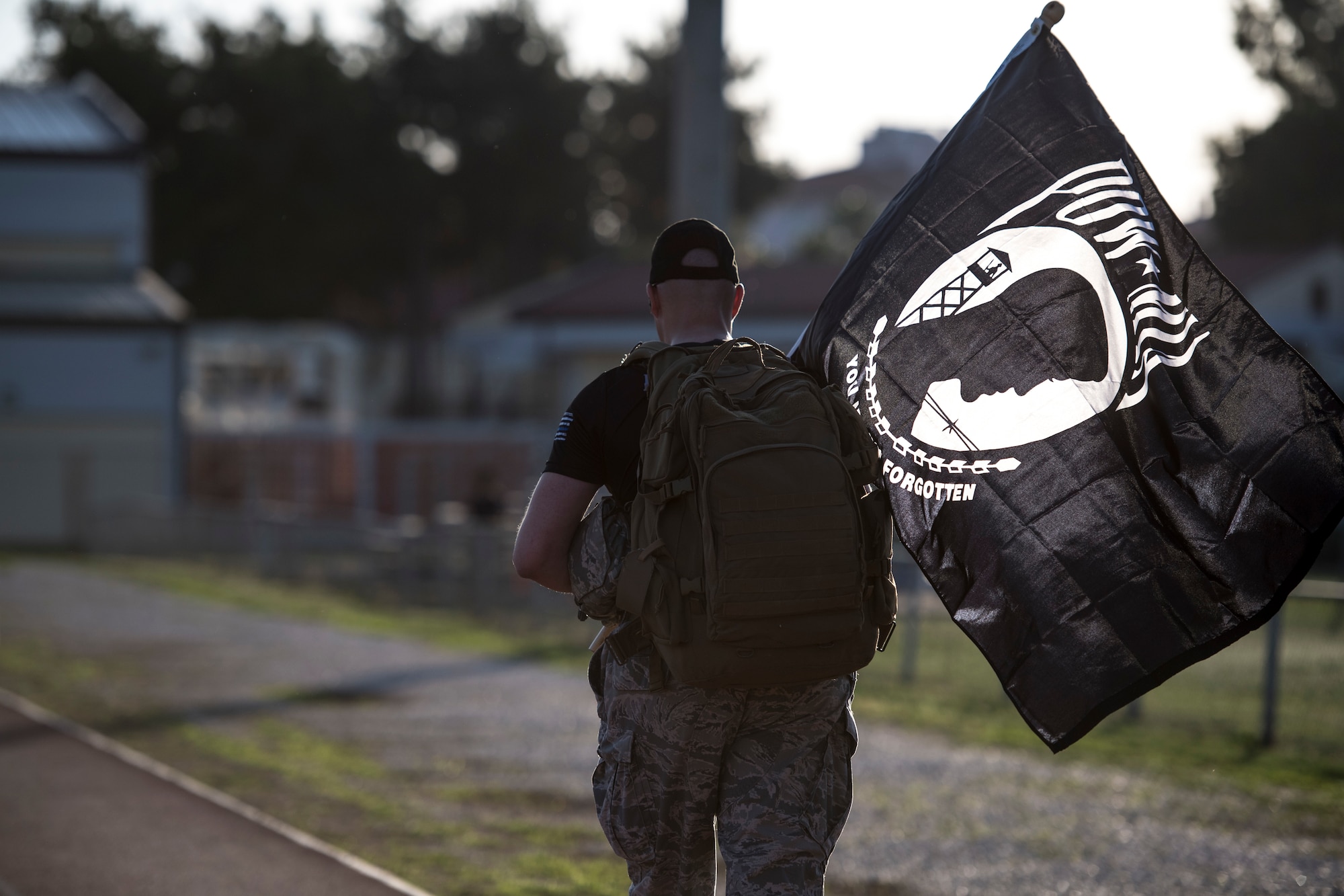 Airman walks during ruck march holding POW/MIA flag