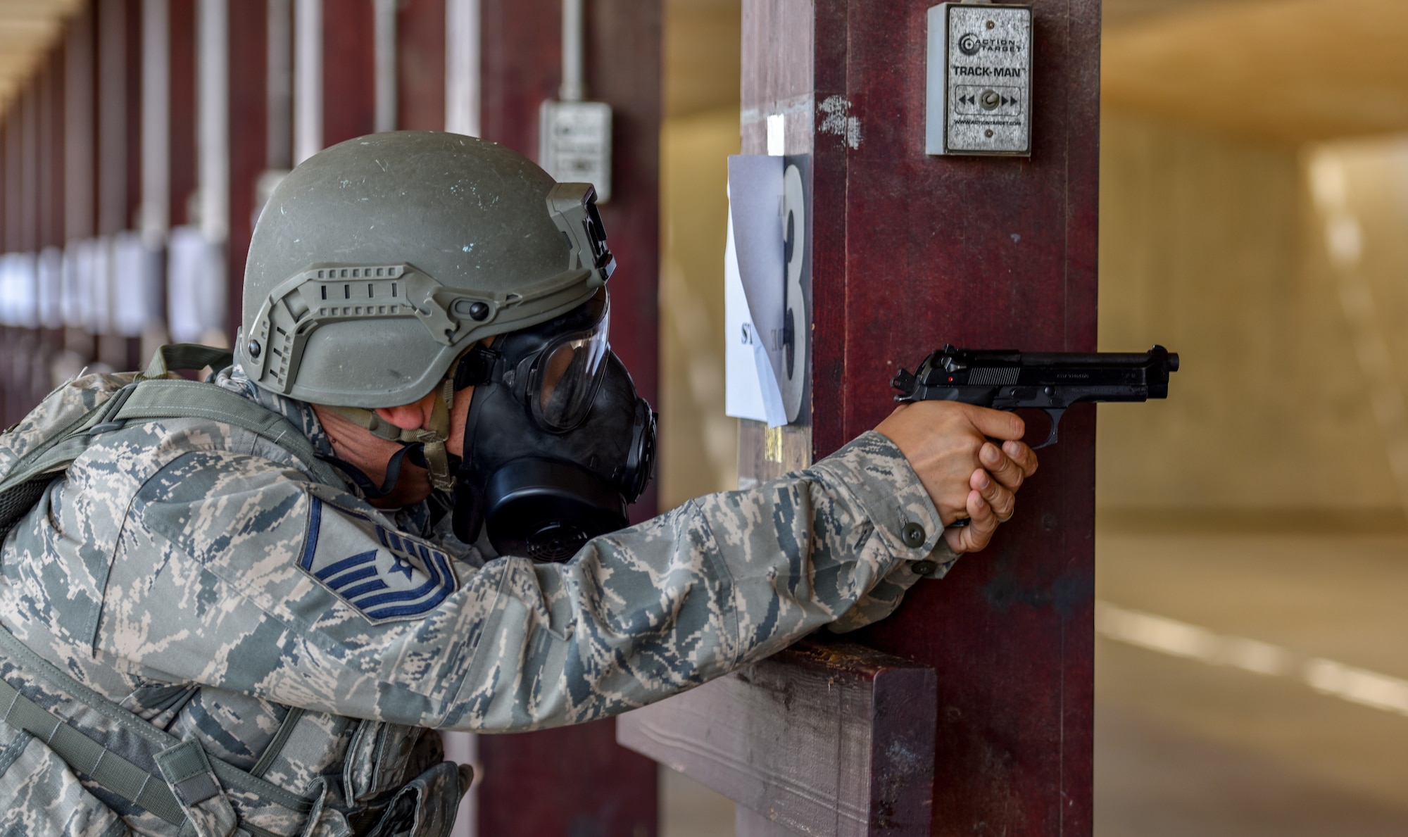 Airmen uses wooden beam to brace himself while firing M9 pistol.