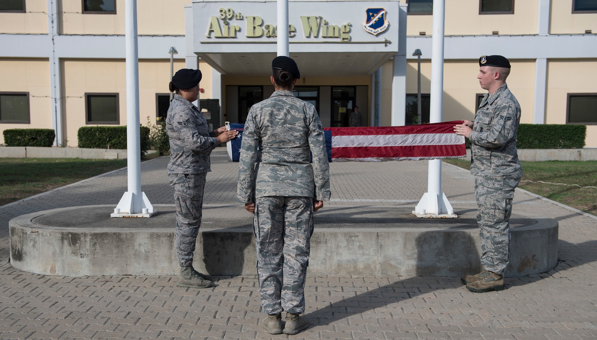 Three Airmen folding an American Flag