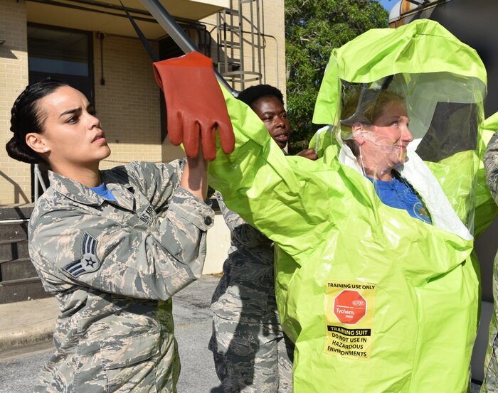U.S. Air Force Senior Airman Dannyel Butte, 325th Aerospace Medicine Squadron bioenvironmental engineering journeyman, assists Lt. Col. Linda Coates, 325th Aerospace Medicine Squadron commander, don a chemical protective suit.