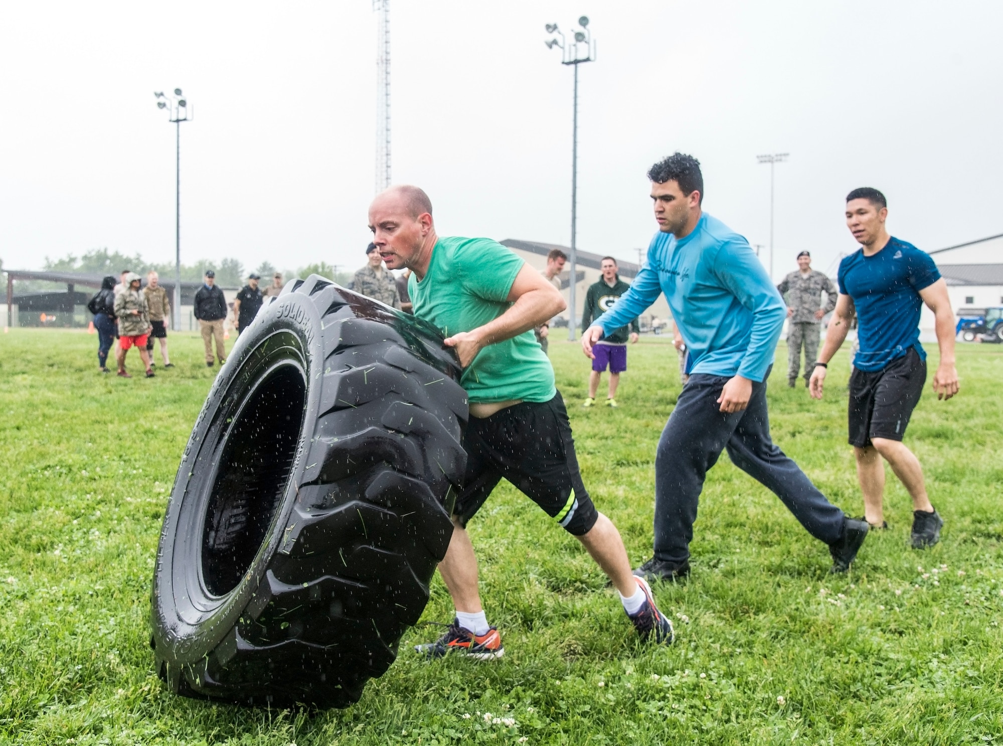 Representing the 436th Communications Squadron, from left, Master Sgt. John Eckert, Senior Airman Jeffrey Bailey-Oqueli, Airman 1st Class Rylan Phungtake turns flipping a tire during the Police Week Combat Fitness Challenge May 17, 2018, at Dover Air Force Base, Del. Five teams completed the nine fitness challenges competing for the fastest overall team time. (U.S. Air Force photo by Roland Balik)