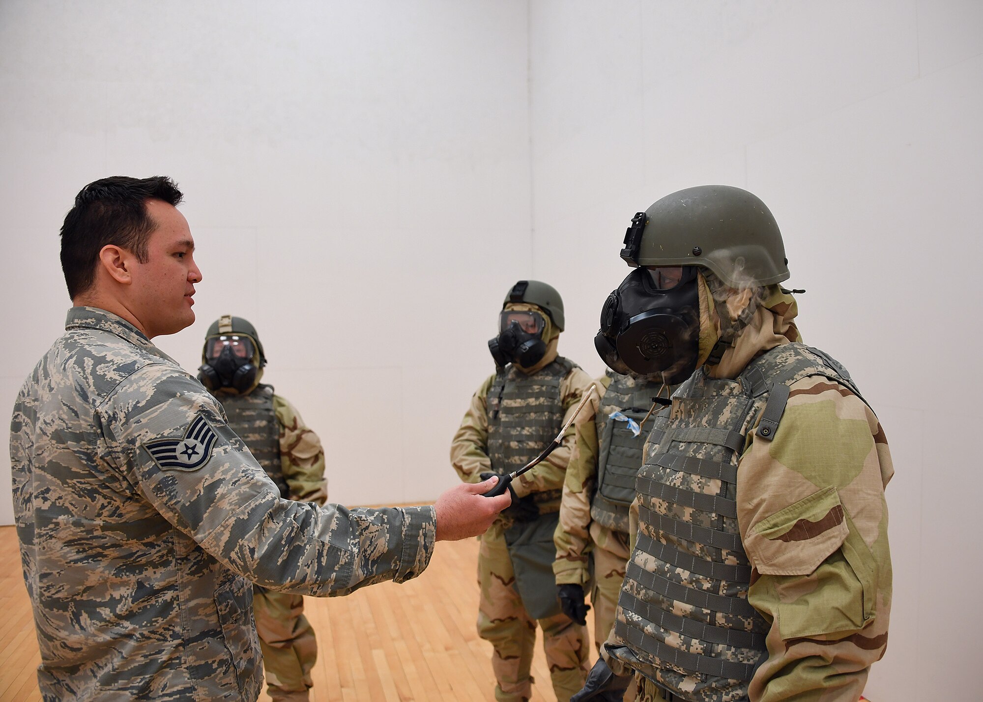 Staff Sgt. Jeremy Breillatt, emergency management craftsman with the 319th Civil Engineer Squadron, left, puffs stannic chloride gas towards Tech. Sgt. Andres Dominguez, noncommissioned officer in charge of relocations with the 319th Force Support Squadron, to test the seal of his gas mask during a readiness competition May 18, 2018, on Grand Forks Air Force Base, North Dakota. Airmen were tested on their ability to put on mission oriented protective posture gear, in addition to providing self-aid and buddy care, weapons assembly and map-reading during the competition. (U.S. Air Force photo by Airman 1st Class Elora J. Martinez)