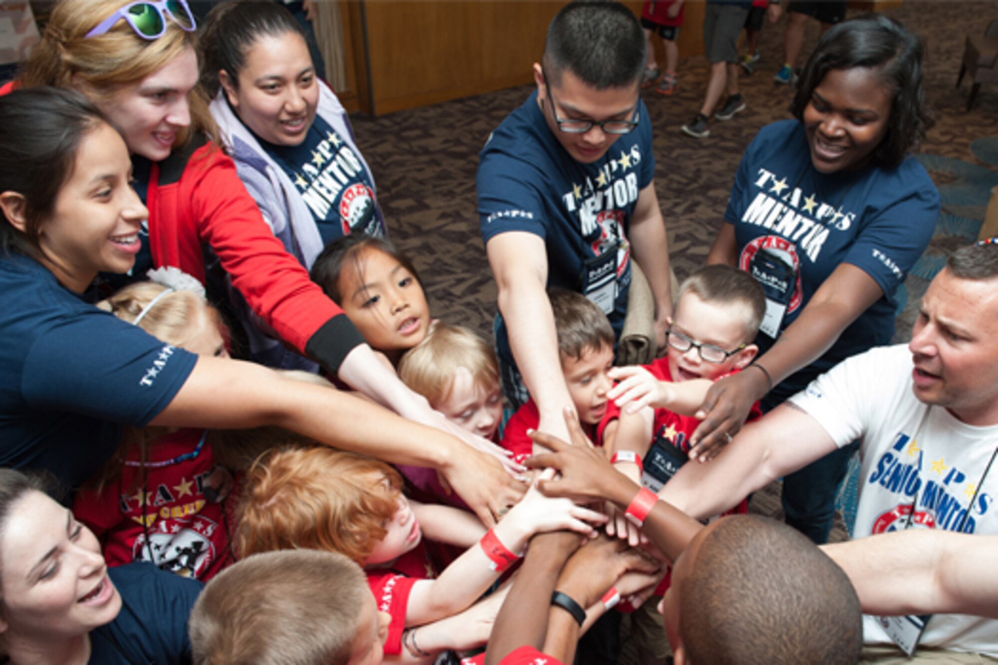 Mentors and children put their hands together for a cheer.