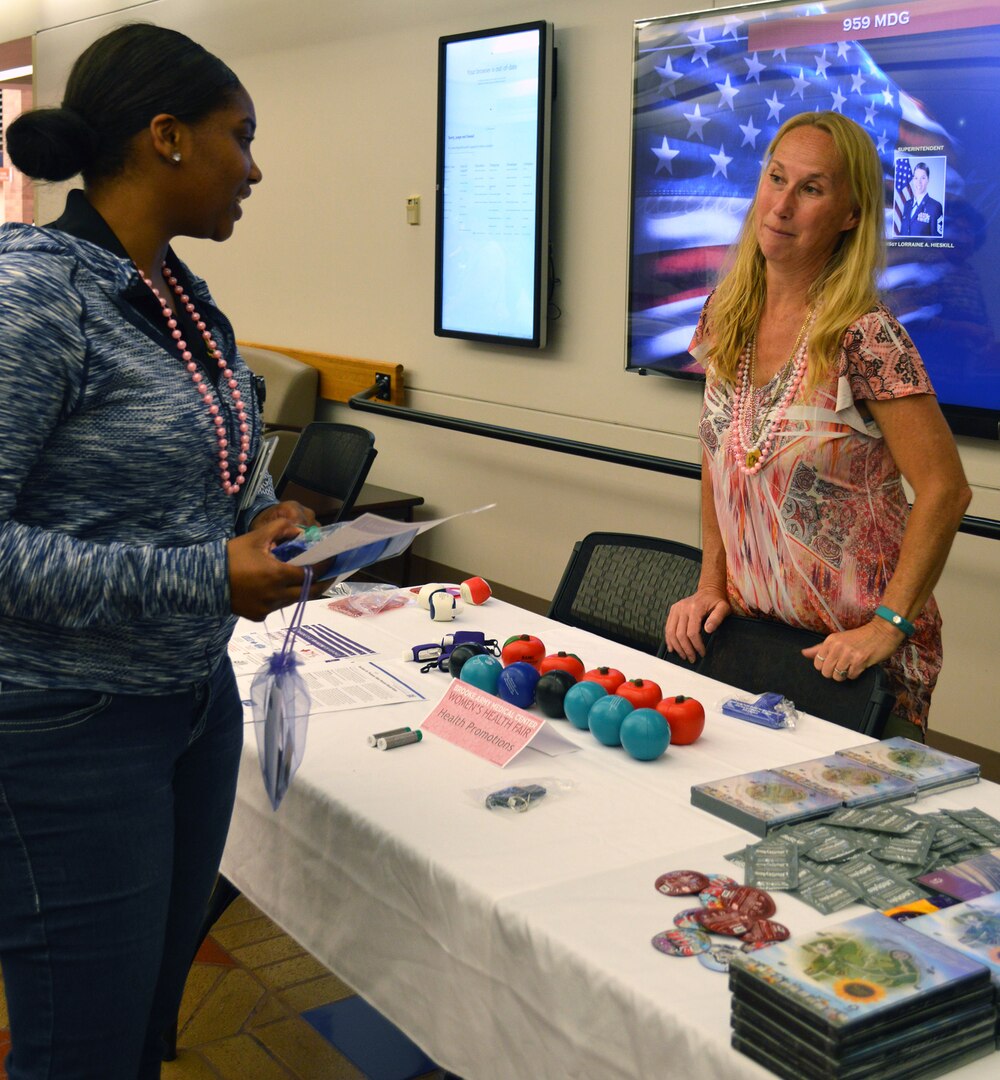 Symone Lofton (left), information desk clerk, talks with Beverly Benson at the health promotions table May 19 at Brooke Army Medical Center’s Women’s Health Fair.