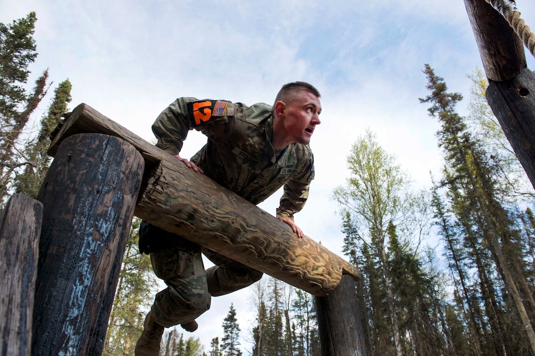 A soldier climbs an obstacle.