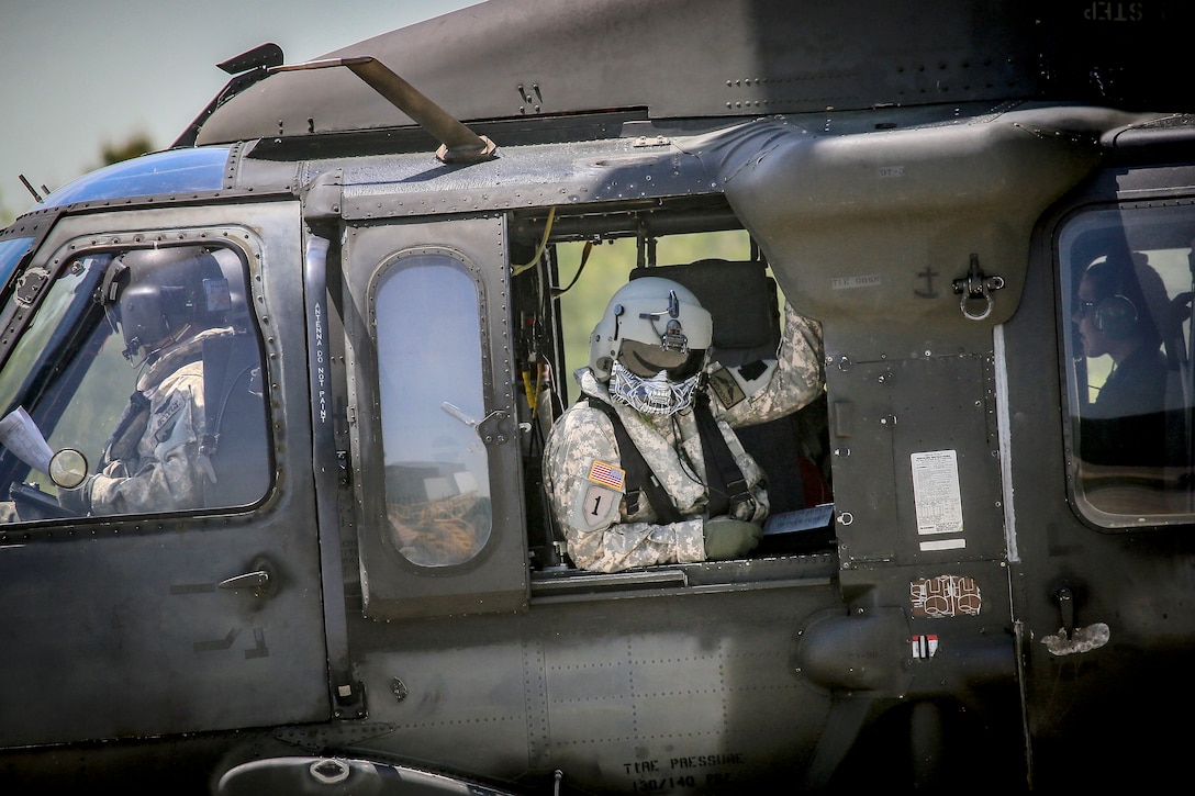 An Army crew chief sits in the gunner’s seat helicopters.