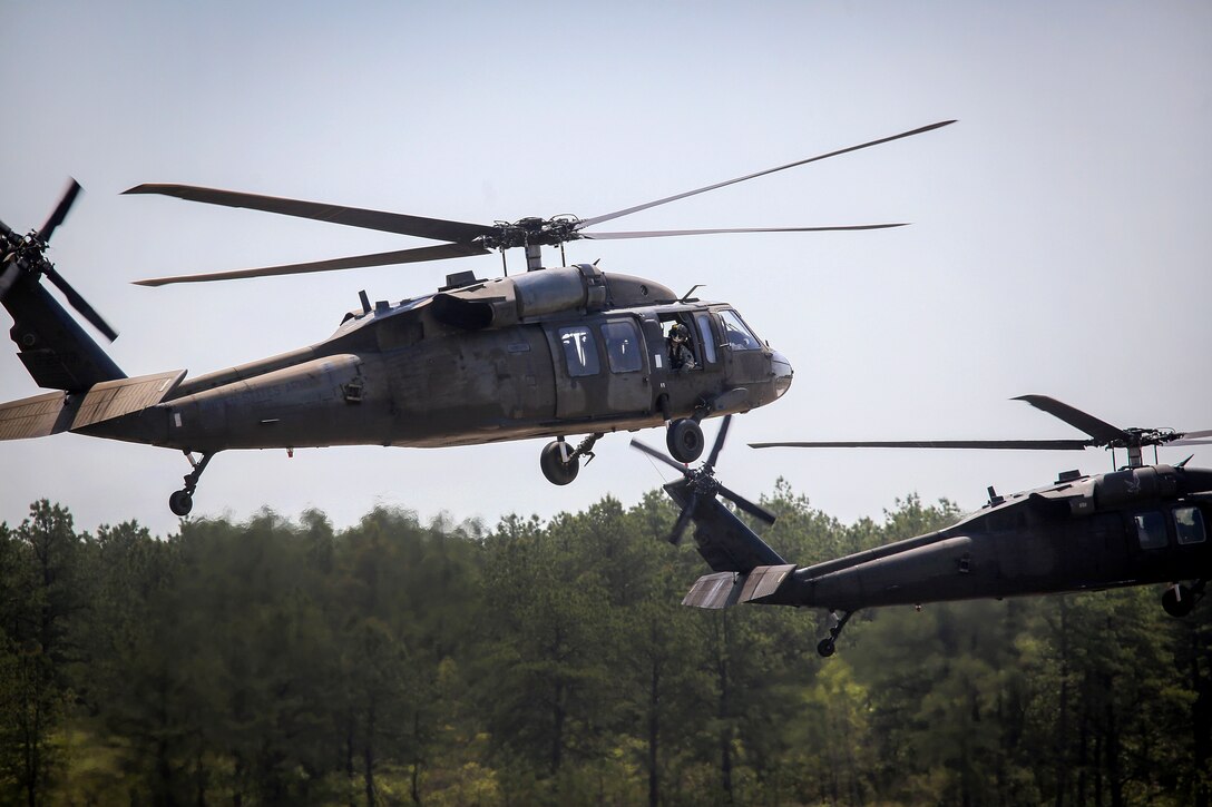 Two Army UH-60L Black Hawk helicopters take off.