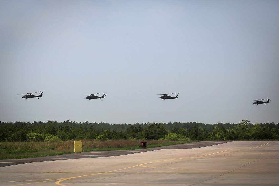 Four Army UH-60L Black Hawk helicopters fly in formation.