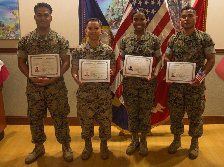 CAMP FOSTER, OKINAWA, Japan – From left to right, Lance Cpl. Henry Eveluck, Sgt. Calvin Torrente, Pfc. Tresharna Black, and Sgt. Nelson Sigrah pose with their naturalization certificates after a naturalization ceremony May 17 hosted at the Ocean Breeze aboard Camp Foster, Okinawa, Japan.