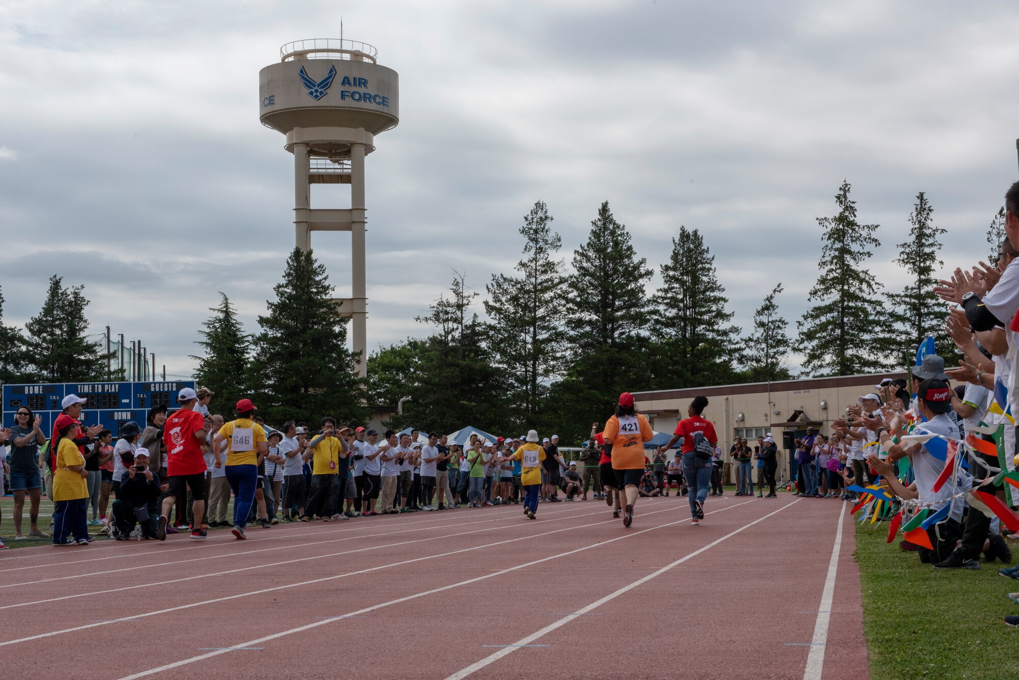 Athletes with their athlete buddies sprint to the finish line of the 50 meter race during the Kanto Plains Special Olympics at Yokota Air Base, Japan, May 19, 2018.