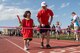 An athlete and her athlete buddy run through the finish line of 4x100 meter relay race during the Kanto Plains Special Olympics at Yokota Air Base, Japan, May 19, 2018.