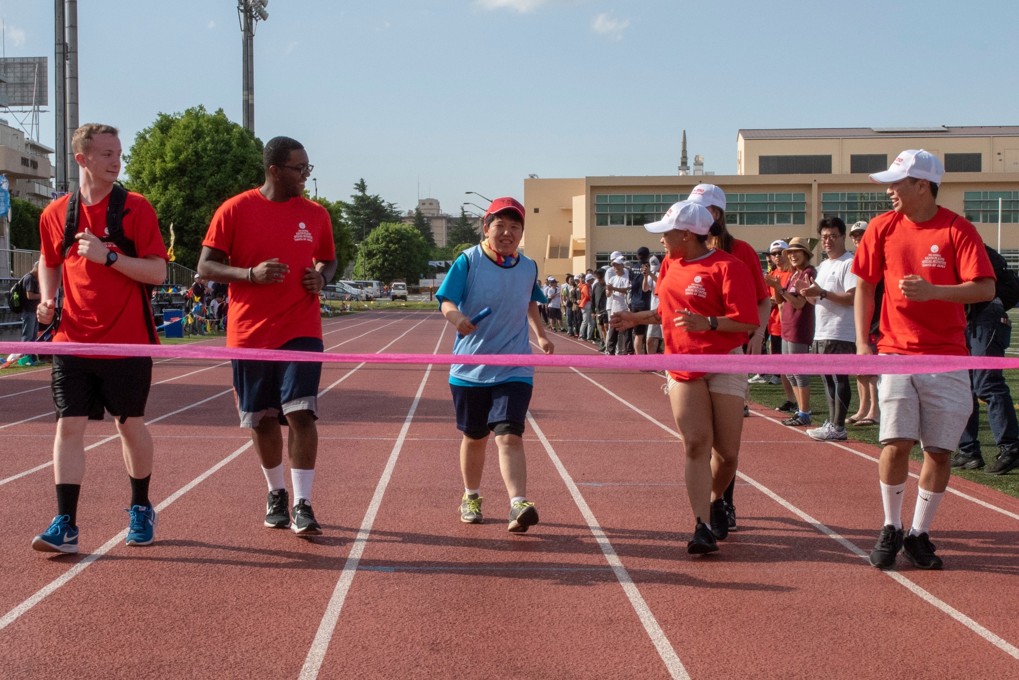 Five volunteer athlete buddies cheer on an athlete during the 4x100 meter relay race during the Kanto Plains Special Olympics at Yokota Air Base, Japan, May 19, 2018.