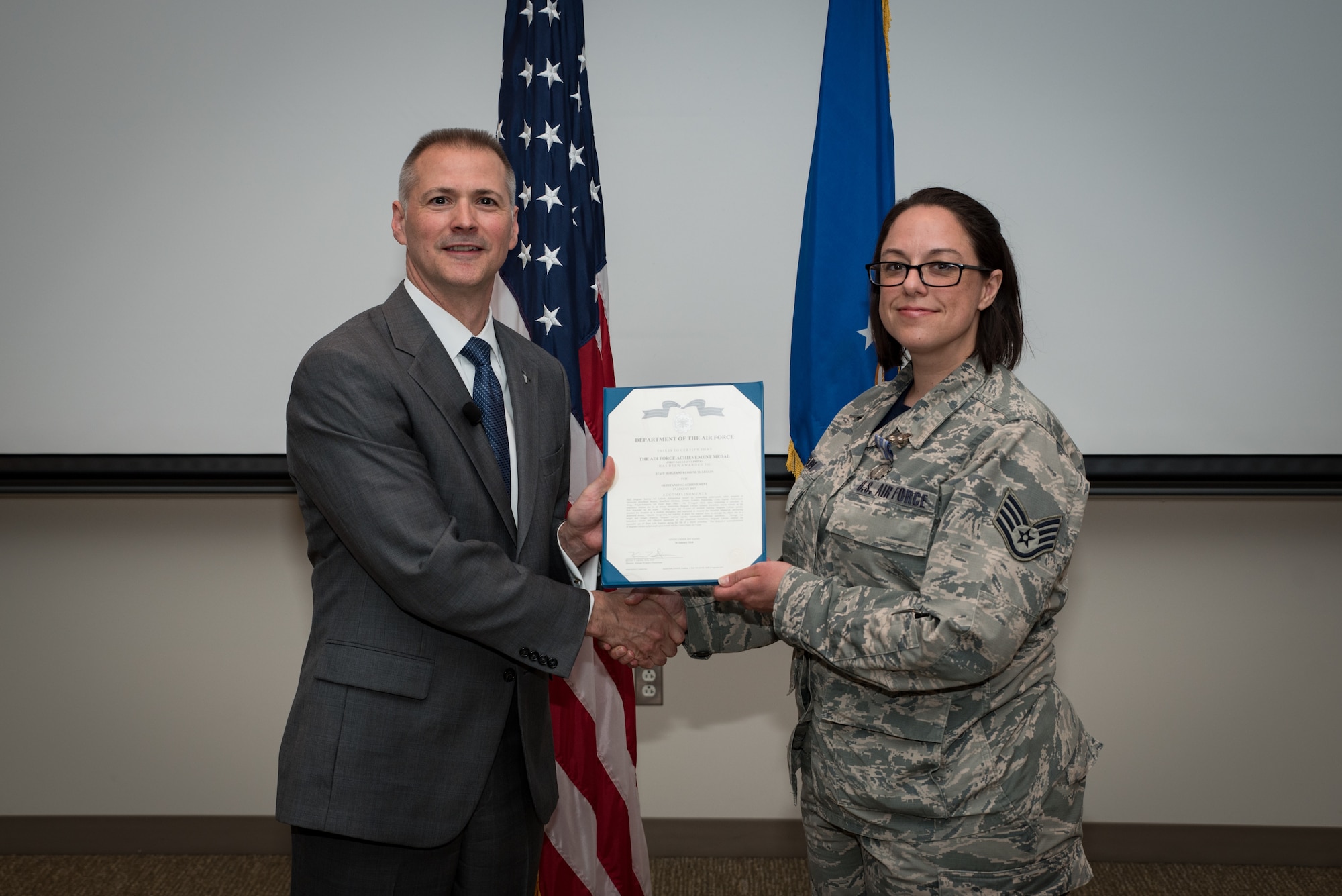 Staff Sgt. Kerrine Leguin stands with Dr. Kevin Geiss, Airman Systems Directorate director, after being awarded with the Air Force Achievement Medal. Leguin heard a coworker in distress, signaled for help from another Airman, and ultimately, rescued the choking coworker. (U.S. Air Force photo/Richard Eldridge)