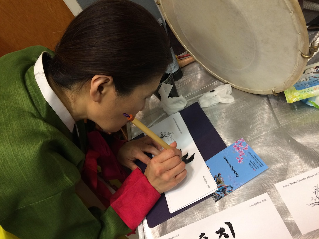 A committee volunteer writes the name of an attendee in Korean caligraphy at the Asian American Pacific Islander Heritage event at the Event Center on Goodfellow Air Force Base, Texas, May 18, 2018. The event helped inform base members about the different cultures during AAPIH month. (U.S. Air Force photo by Aryn Lockhart/Released)