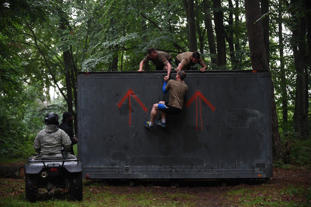 Kaiserslautern Military Community service members work together to climb over a wall during the 2018 Ramstein Mudder, May 24 at Ramstein Air Base, Germany. More than 200 Kaiserslautern Military Community Members ran the 2.5 mile obstacle course for the 86th Airlift Wing’s resilience day. (U.S. Air Force photo by Staff Sgt. Nesha Humes Stanton)