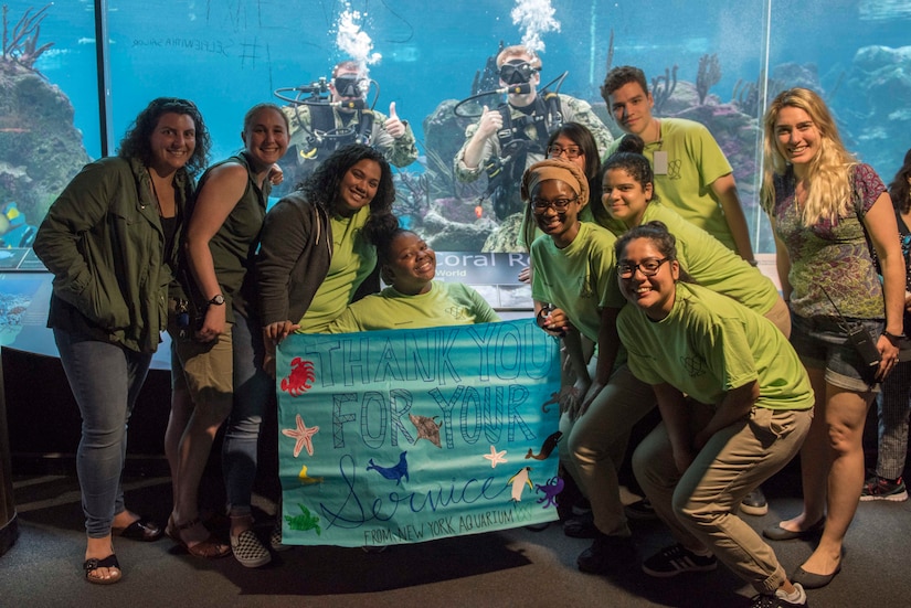 Navy divers pose in water inside New York Aquarium.