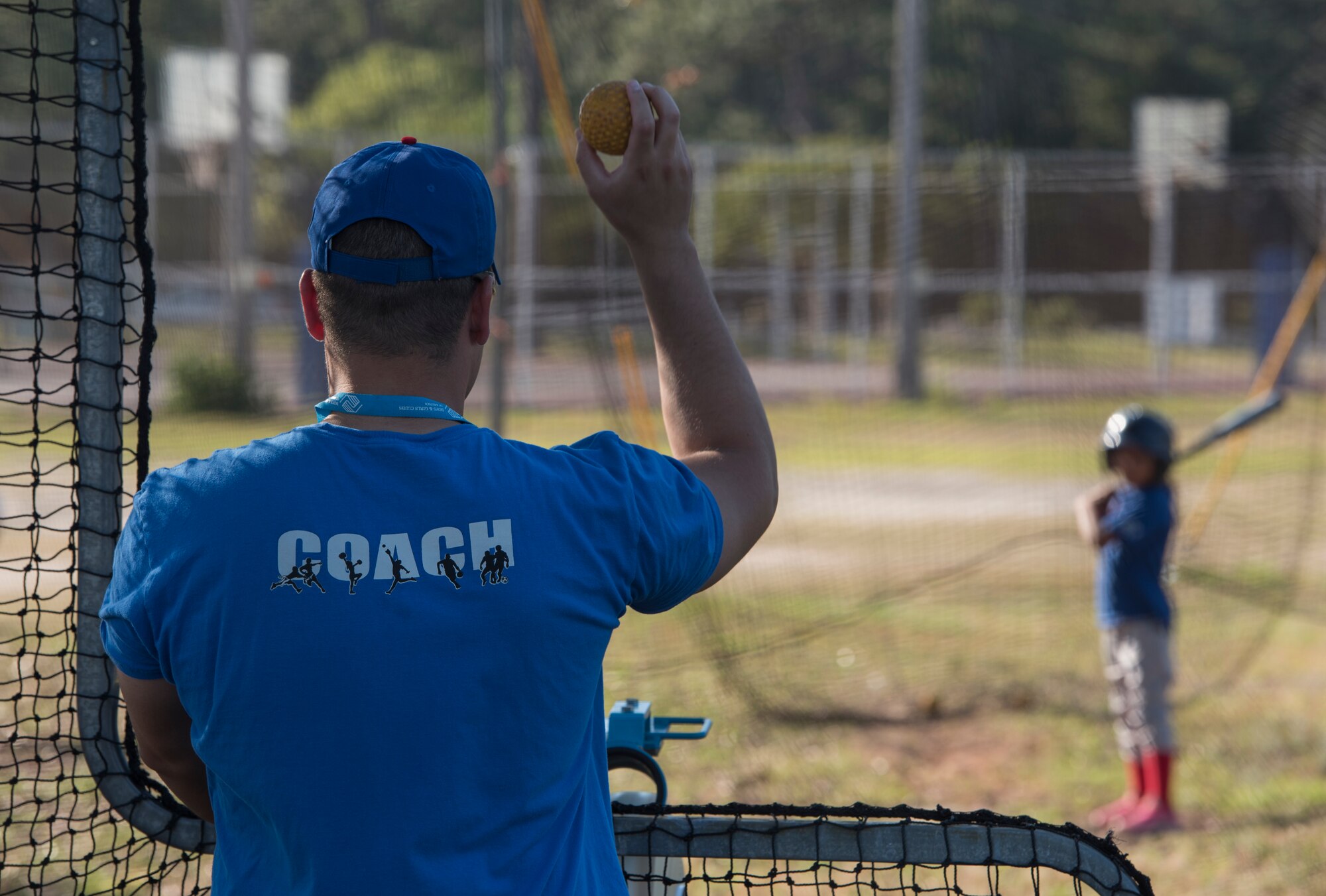 U.S. Air Force Capt. Joshua Gradaille, 33rd Fighter Wing executive officer, shows a practice ball to one of his players before putting it in a pitching machine May 10, 2018, at Eglin Air Force Base, Fla. Gradaille started coaching children's baseball on base more than two years ago when he found himself watching his son from the bleachers and feeling he could make an impact. (U.S. Air Force photo by Staff Sgt. Peter Thompson)