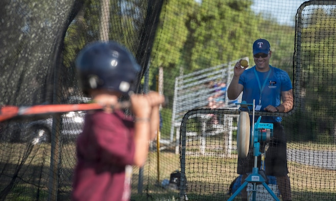 U.S. Air Force Capt. Joshua Gradaille, 33rd Fighter Wing executive officer, shows a practice ball to one of his players before putting it in a pitching machine May 10, 2018, at Eglin Air Force Base, Fla. Gradaille enrolled his son in baseball when he was five years old to instill the many life lessons he feels team sports offer a child. (U.S. Air Force photo by Staff Sgt. Peter Thompson)