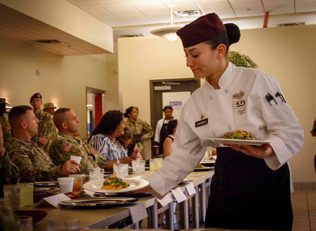 Military chef serves a course during a competition.