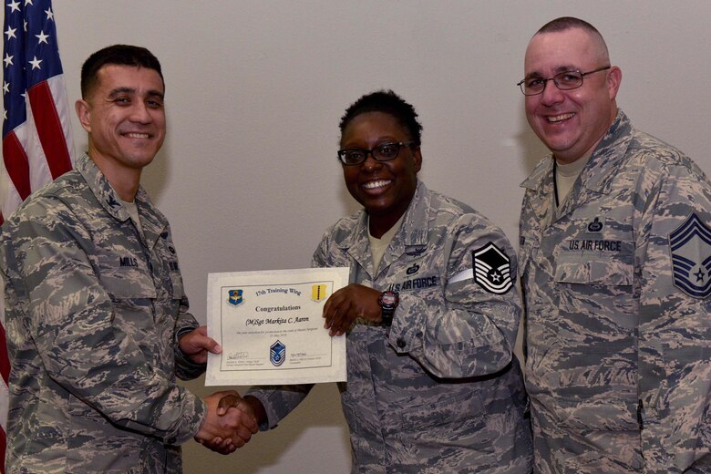 U.S. Air Force Col. Ricky Mills, 17th Training Wing commander, presents Tech. Sgt. Markita Aaron, 316th Training Squadron instructor, their certificate of selection with Chief Master Sgt. Daniel Stein, 17th TRW command chief, during a Master Sergeant release party at the Event Center on Goodfellow Air Force Base, Texas, May 25, 2018. Goodfellow held the party to notify the selected promotees and to give fellow wingmen and friends an opportunity to congratulate them on their success. (U.S. Air Force photo by Senior Airman Randall Moose)