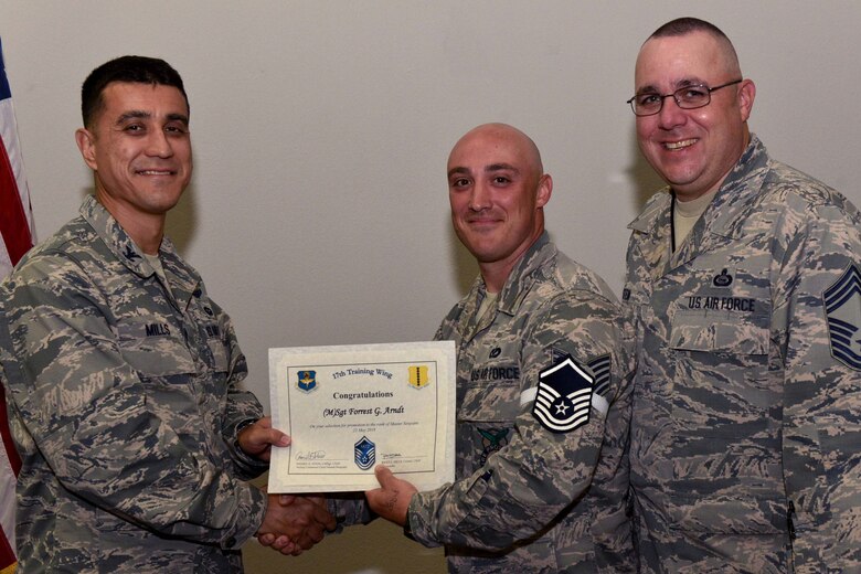 U.S. Air Force Col. Ricky Mills, 17th Training Wing commander, presents Tech. Sgt. Forrest Arndt, 312th Training Squadron instructor, their certificate of selection with Chief Master Sgt. Daniel Stein, 17th TRW command chief, during a Master Sergeant release party at the Event Center on Goodfellow Air Force Base, Texas, May 25, 2018. Goodfellow held the party to notify the selected promotees and to give fellow wingmen and friends an opportunity to congratulate them on their success. (U.S. Air Force photo by Senior Airman Randall Moose)