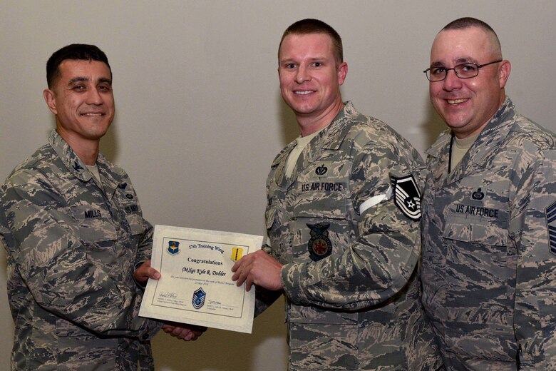 U.S. Air Force Col. Ricky Mills, 17th Training Wing commander, presents Tech. Sgt. Kyle Dobler, 312th Training Squadron instructor, their certificate of selection with Chief Master Sgt. Daniel Stein, 17th TRW command chief, during a Master Sergeant release party at the Event Center on Goodfellow Air Force Base, Texas, May 25, 2018. Goodfellow held the party to notify the selected promotees and to give fellow wingmen and friends an opportunity to congratulate them on their success. (U.S. Air Force photo by Senior Airman Randall Moose)