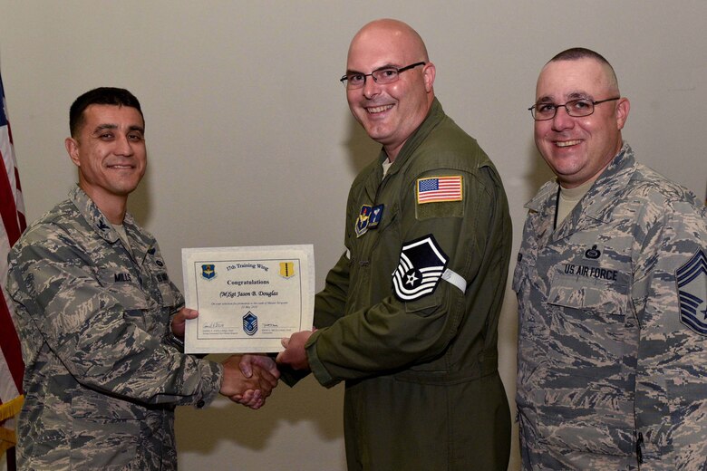 U.S. Air Force Col. Ricky Mills, 17th Training Wing commander, presents Tech. Sgt. Jason Douglas, 316th Training Squadron instructor, their certificate of selection with Chief Master Sgt. Daniel Stein, 17th TRW command chief, during a Master Sergeant release party at the Event Center on Goodfellow Air Force Base, Texas, May 25, 2018. Goodfellow held the party to notify the selected promotees and to give fellow wingmen and friends an opportunity to congratulate them on their success. (U.S. Air Force photo by Senior Airman Randall Moose)