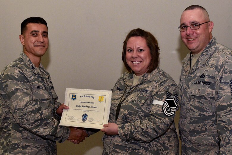 U.S. Air Force Col. Ricky Mills, 17th Training Wing commander, presents Tech. Sgt. Kendra Farmer, 315th Training Squadron instructor, their certificate of selection with Chief Master Sgt. Daniel Stein, 17th TRW command chief, during a Master Sergeant release party at the Event Center on Goodfellow Air Force Base, Texas, May 25, 2018. Goodfellow held the party to notify the selected promotees and to give fellow wingmen and friends an opportunity to congratulate them on their success. (U.S. Air Force photo by Senior Airman Randall Moose)