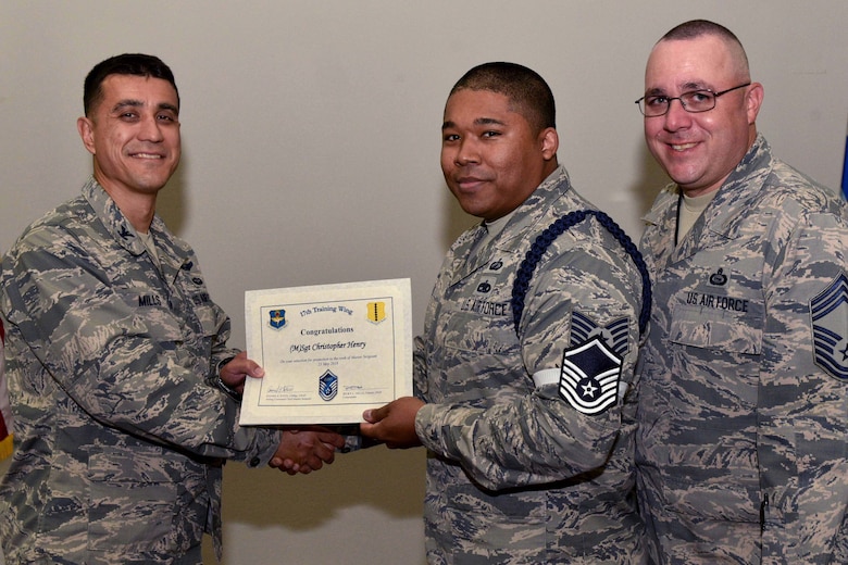 U.S. Air Force Col. Ricky Mills, 17th Training Wing commander, presents Tech. Sgt. Christopher Henry, 316th Training Squadron instructor, their certificate of selection with Chief Master Sgt. Daniel Stein, 17th TRW command chief, during a Master Sergeant release party at the Event Center on Goodfellow Air Force Base, Texas, May 25, 2018. Goodfellow held the party to notify the selected promotees and to give fellow wingmen and friends an opportunity to congratulate them on their success. (U.S. Air Force photo by Senior Airman Randall Moose)