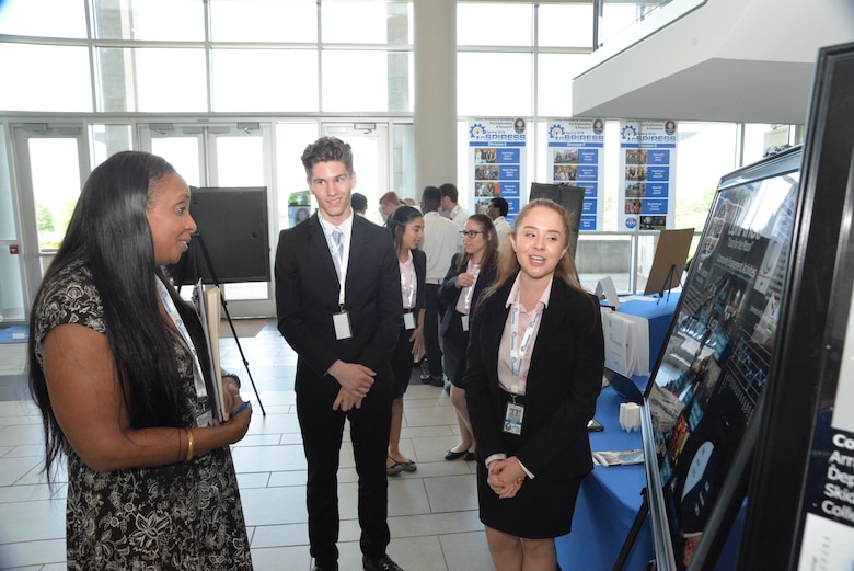 Luisa Mercado, right, a student from Da Vinci School for Science and The Arts in El Paso, Texas, explains her team’s project May 11, 2018, to Lori Cordell-Meikle, chief of Internal Review for Huntsville Center, as part of the Innovative System Project for the Increased Recruitment of Emerging STEM Students at the University of Alabama in Huntsville. Mercado, who served as a community engagement activity leader for her team, stands next to Sebastian Contreras, the team’s project manager.